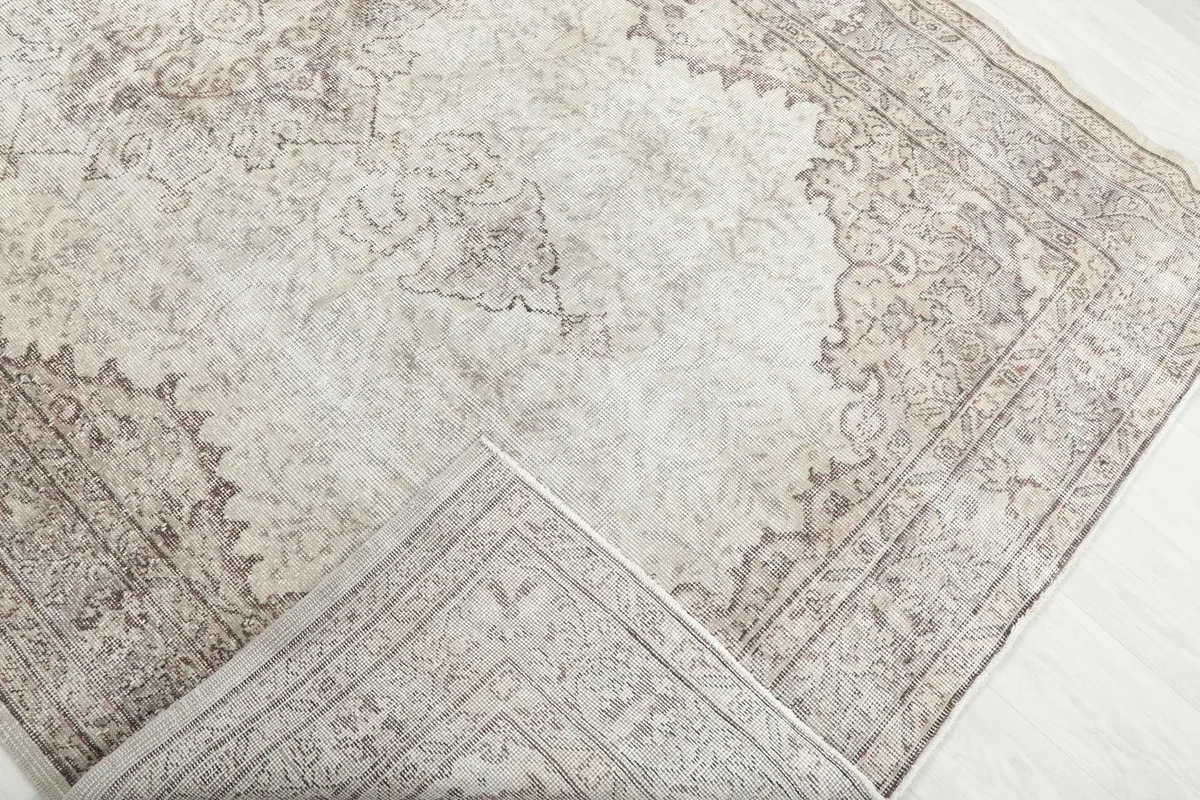 Corner of the rug folded back, revealing the reverse side of the hand-knotted wool construction.