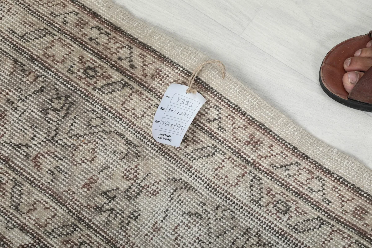 Tag with rug dimensions and material information, placed on the edge of the vintage rug.