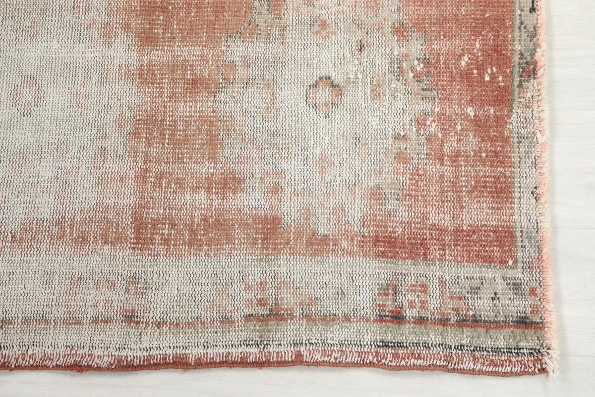 Detailed view of the faded geometric patterns and rust tones on one end of the runner