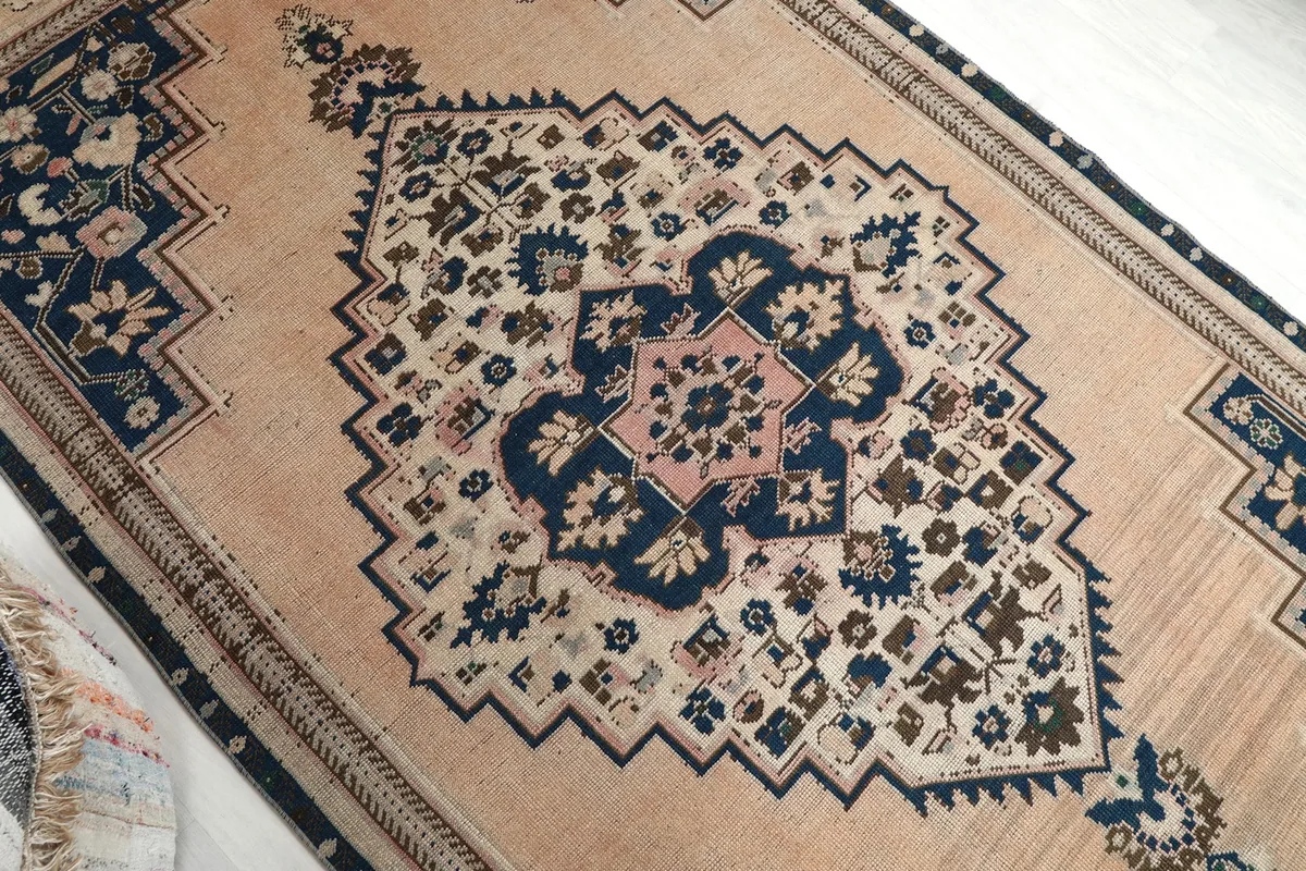 Angled shot focusing on the central navy and rose medallion and surrounding beige field