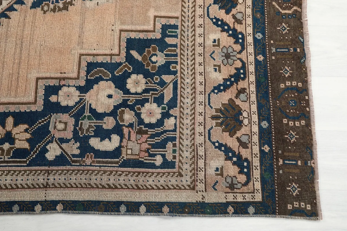 Close-up of the rug's corner, showing the navy and brown border with floral motifs