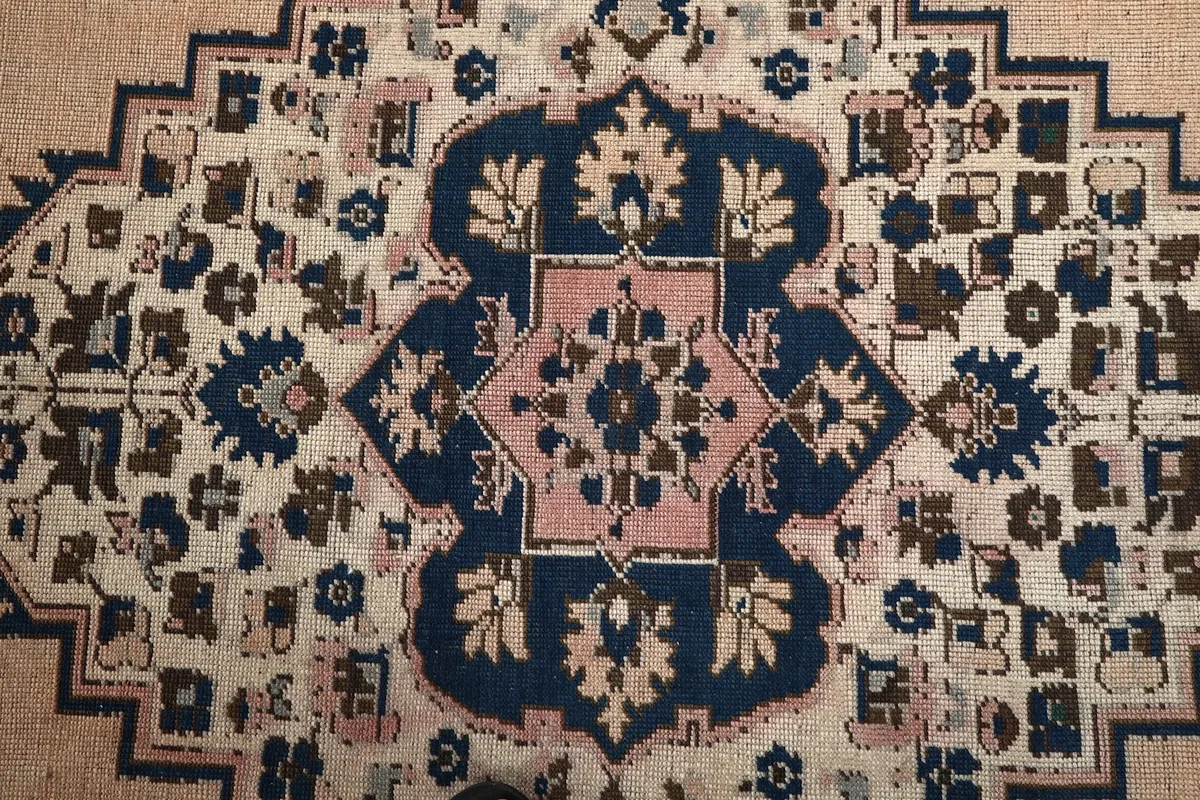 Detailed view of the central medallion with navy, rose, and beige patterns