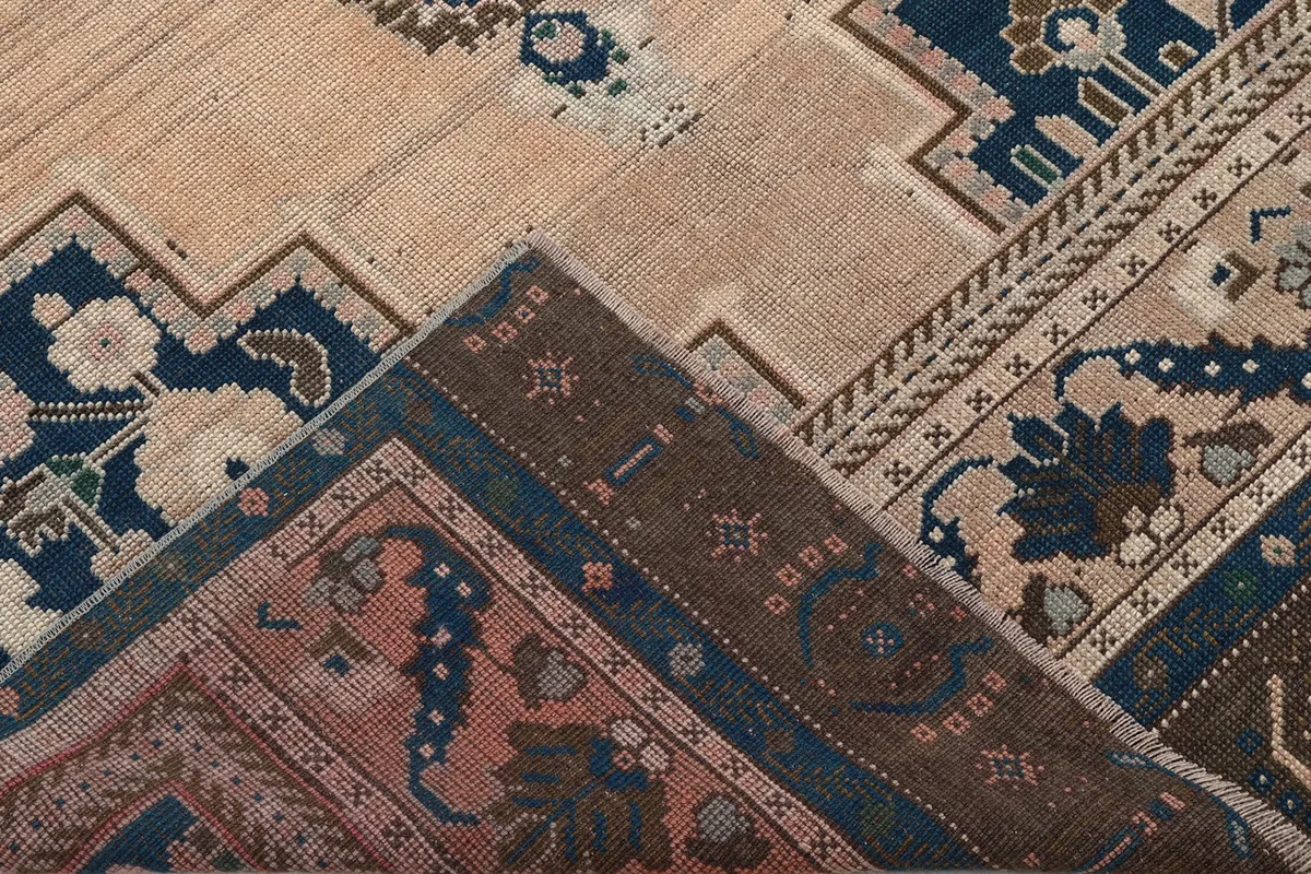Corner of the rug folded back, showing the cotton foundation and reverse side of the knots