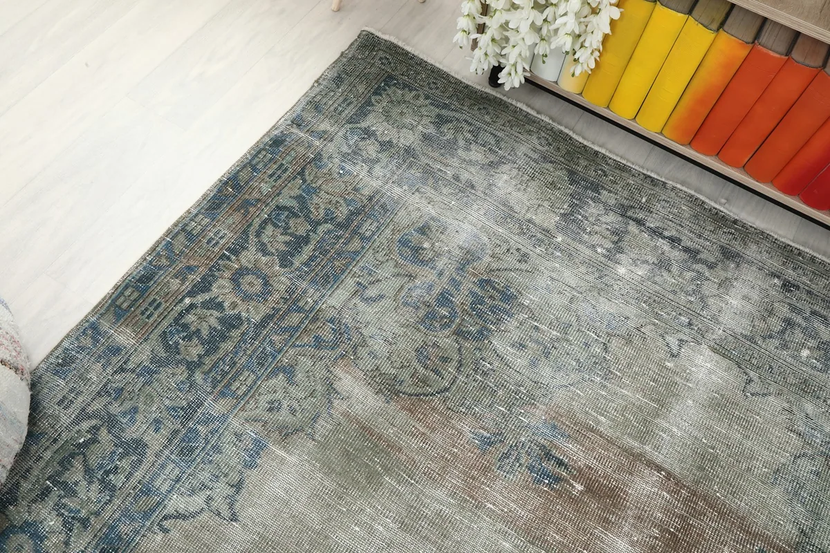 Angled view showing the corner of the rug with its blue border and faded field