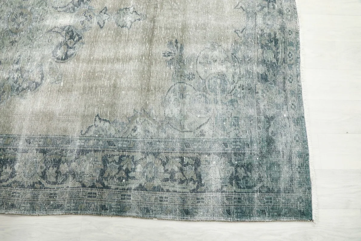 Detail view of the blue border pattern and faded gray field of the vintage rug