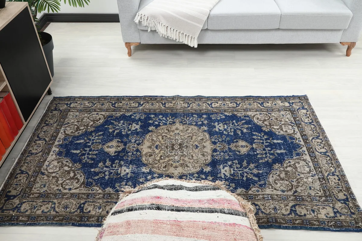 Full room view of the small blue Anatolian rug, providing context for its size and style