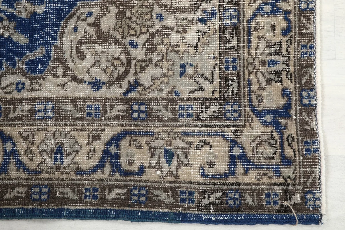 Detailed view of the corner and border design of the blue and beige vintage rug