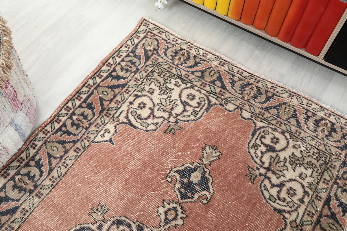 Angled detail of the rug's upper section, showing the rust field, border, and decorative motifs.