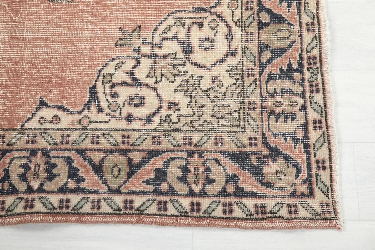 Detailed corner of the rug, highlighting the beige and navy border patterns and fringe.