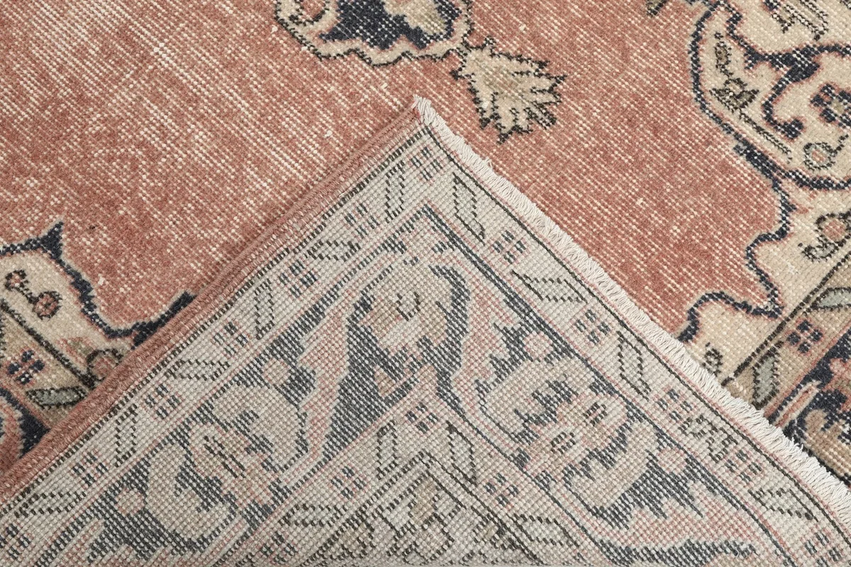 Corner of the rug folded back to reveal the hand-knotted cotton foundation and reverse side.