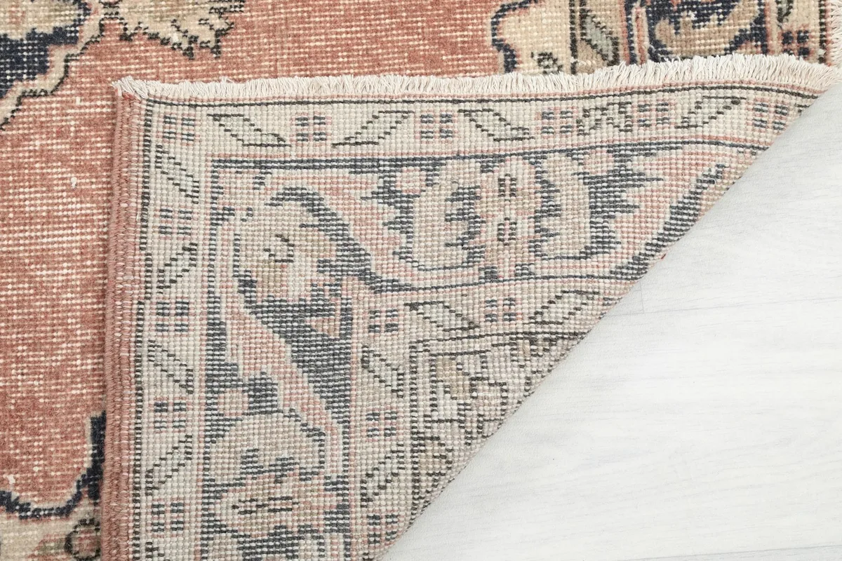 Another view of the rug's corner folded, showing the back of the rug and the fringe.