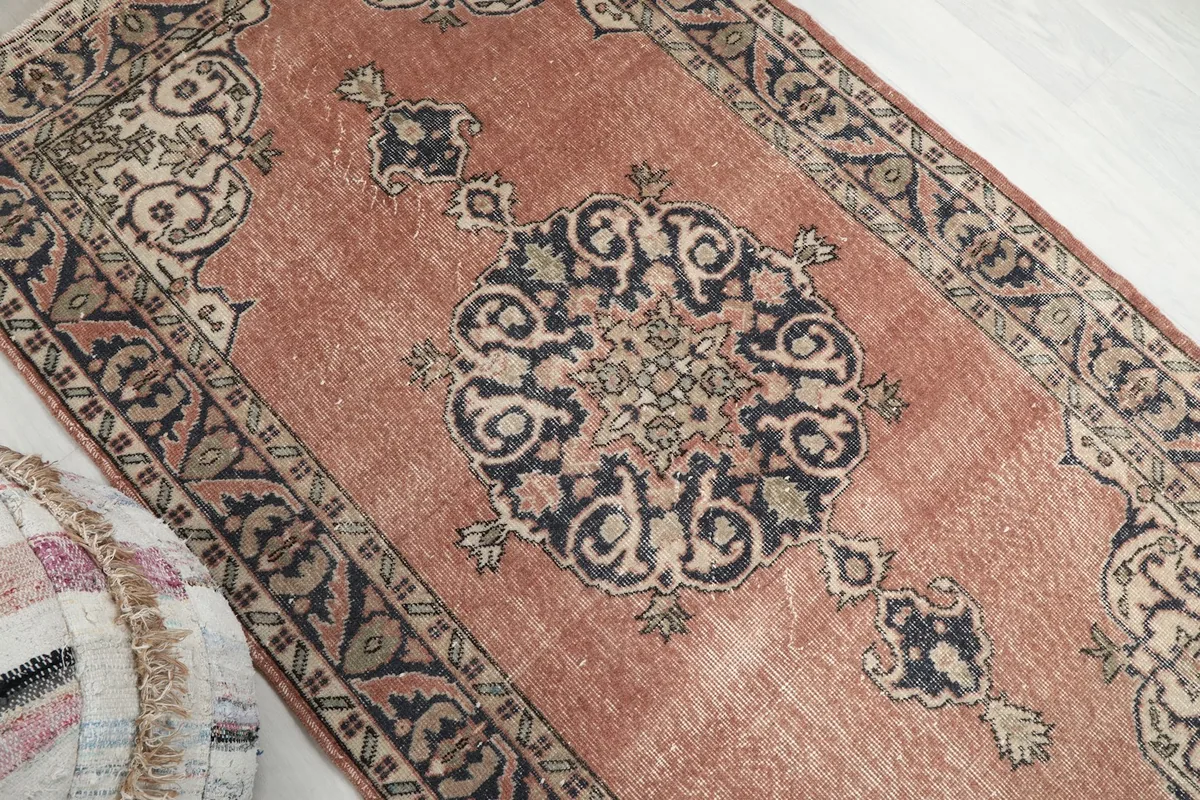 Overhead view focusing on the central navy and beige medallion against the rust field.