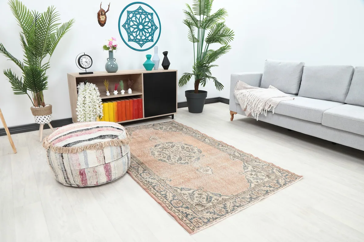 Overhead view of the rose Anatolian rug in a living room, showing its placement relative to a sofa and ottoman.