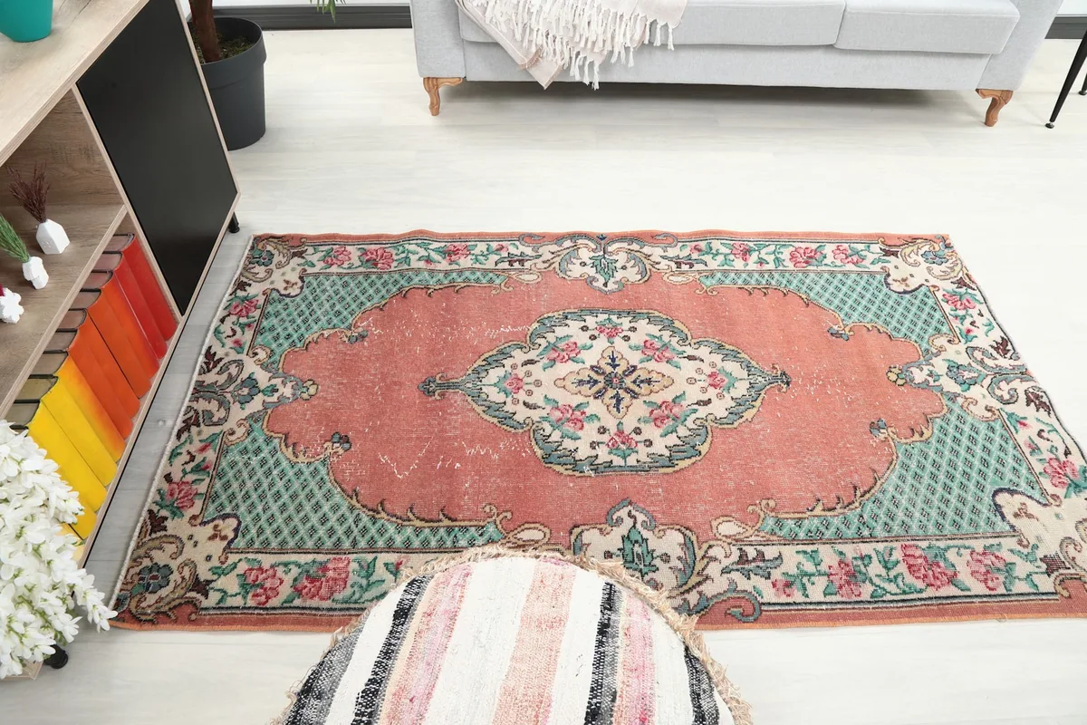 Wider room view showing the rose and green area rug's placement and scale