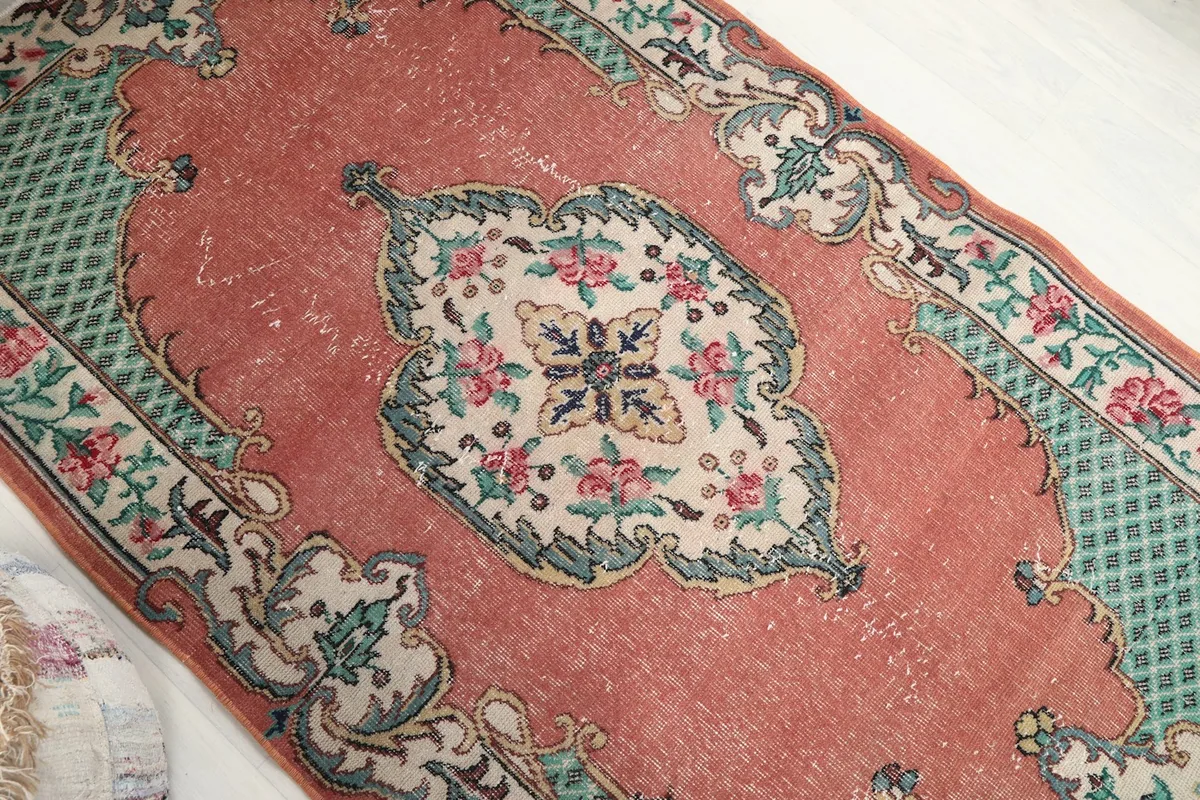 Detailed view of the central medallion with rose and green floral elements on an ivory background