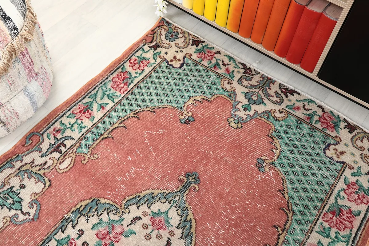 Detail of the rose field, green geometric pattern, and ivory floral border of the rug