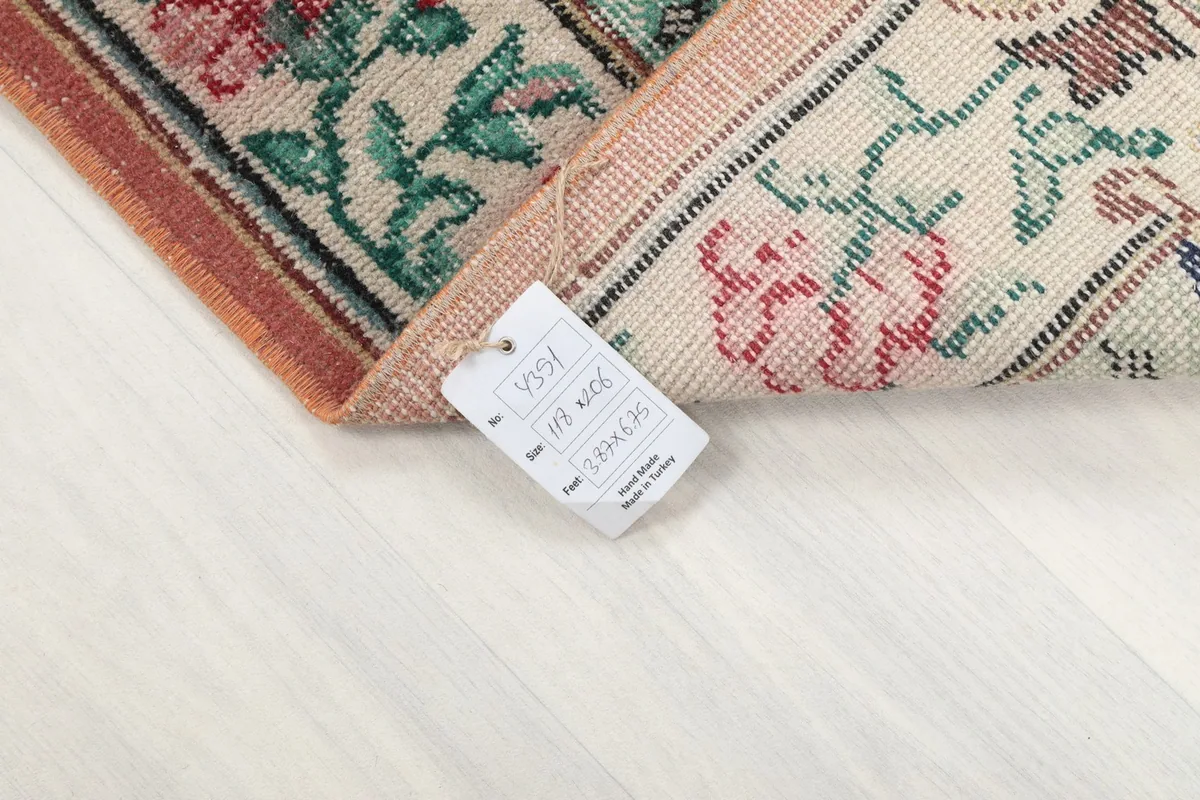 Corner of the rug with a tag indicating its hand-knotted origin and material
