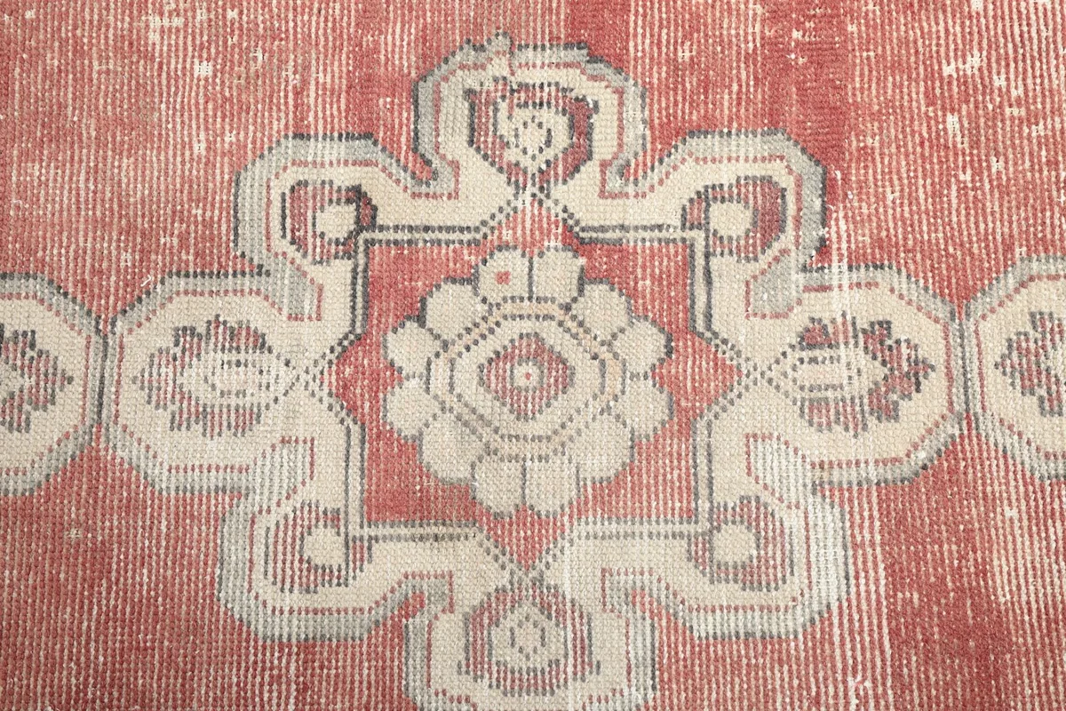 Close-up of a central ivory and gray medallion motif on the rust background