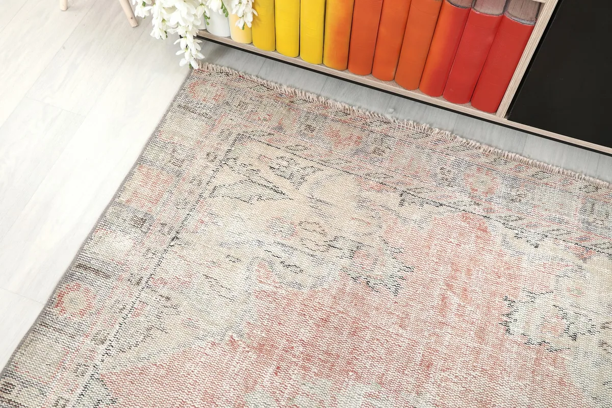 Corner view of the rug, showing the blend of rose, beige, and gray colors.