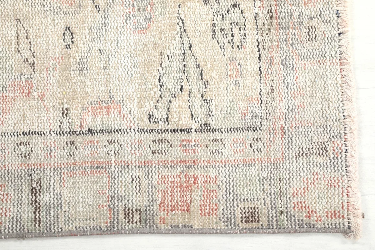 Detailed view of the rug's border design, showing the subtle gray and rose tones.
