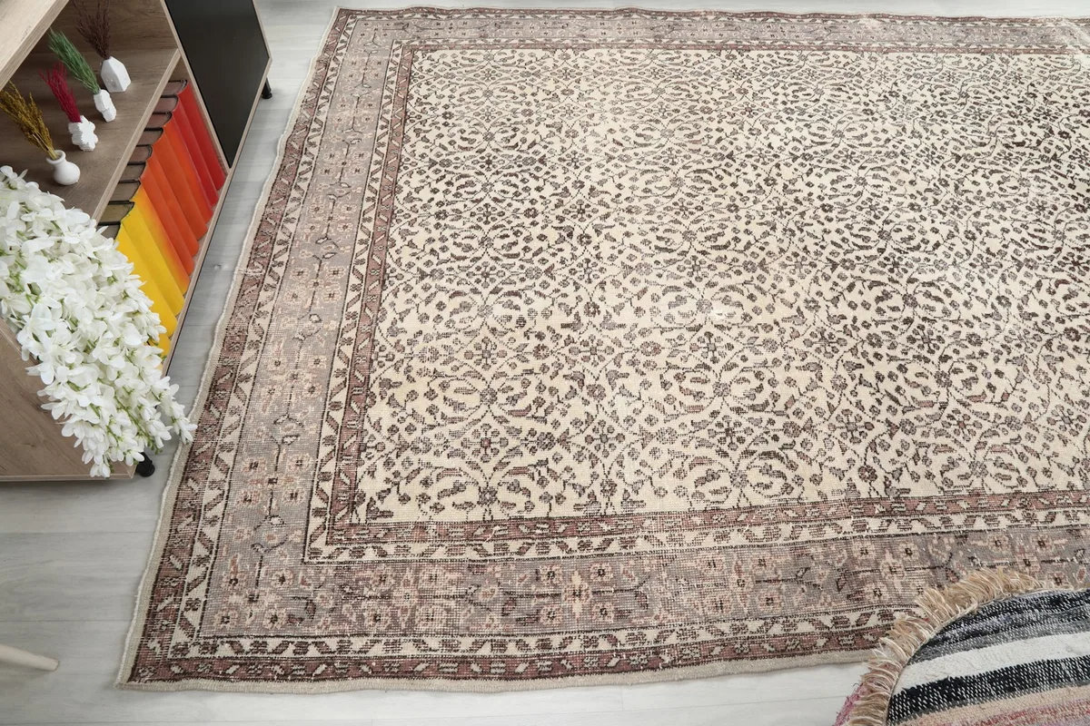 Angled perspective of the vintage wool rug, capturing the soft patina and faded tones of its brown and ivory design.
