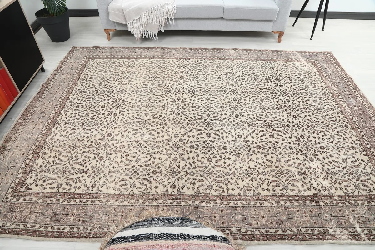 Frontal view of the large 7'3" x 10'1" ivory and brown rug laid out in a living area, seen from a distance.