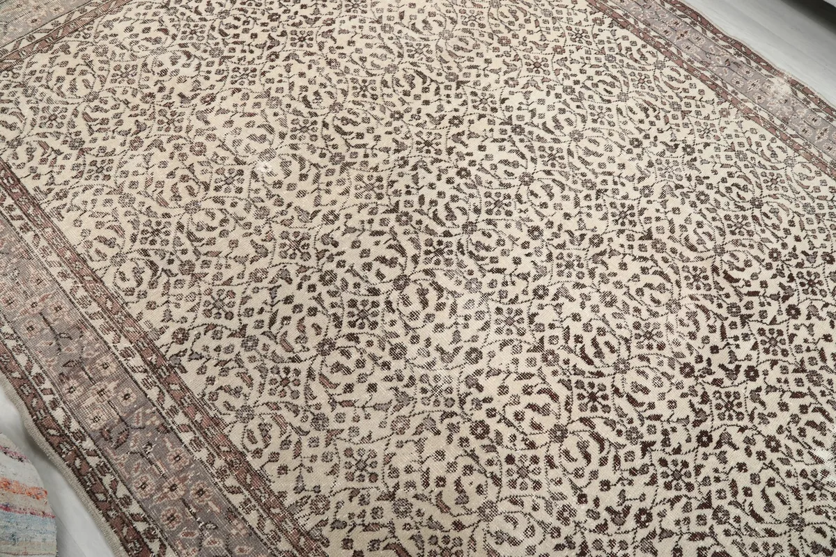 Overhead shot highlighting the overall floral pattern and color variation across the ivory and brown vintage rug.