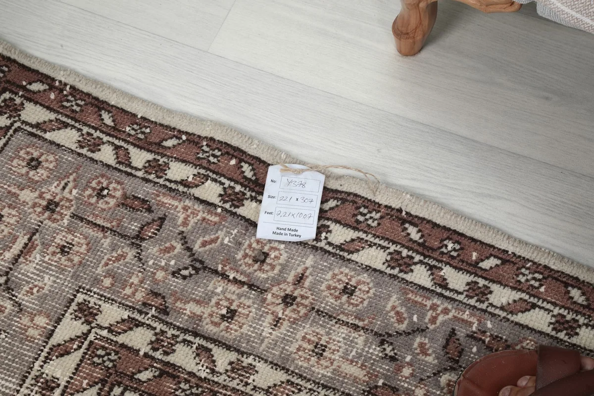 Detail of the rug's edge with a product tag, showing the professional cleaning and vintage quality.