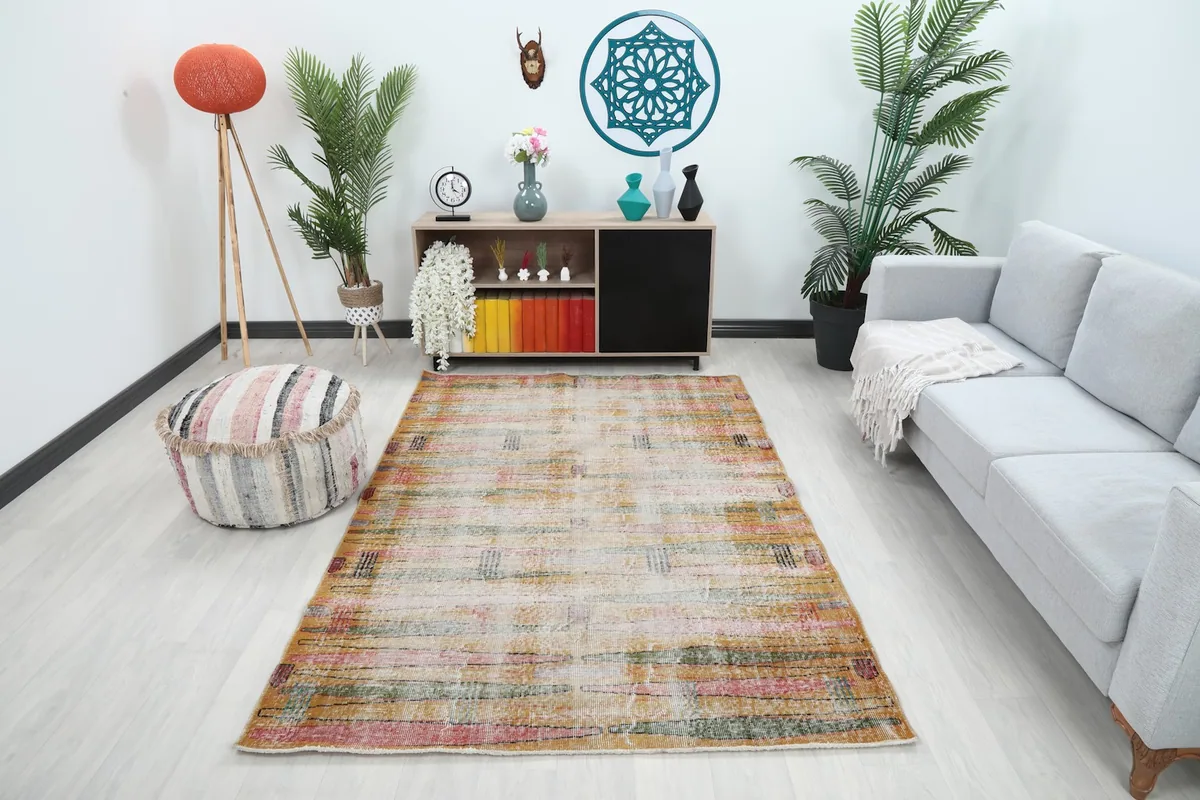 Vintage gold and multicolor rug displayed in a living room setting with a sofa and cabinet