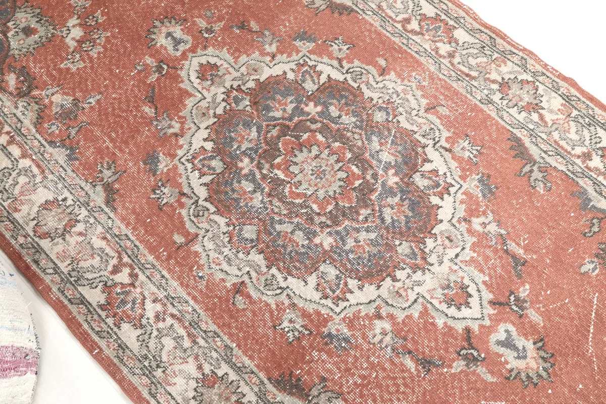 Overhead detail of the rug's central medallion with rust, beige, and blue tones