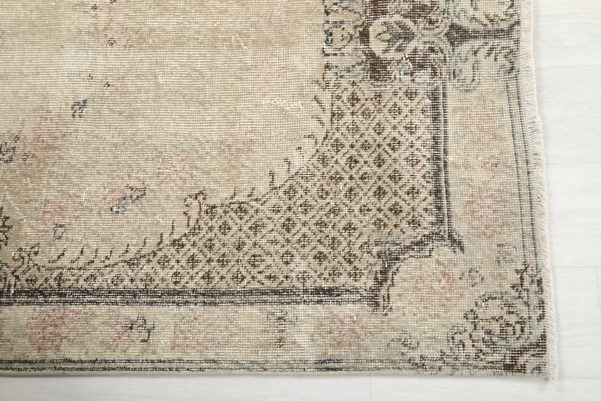 Detail view of the rug's corner with geometric border pattern and beige field