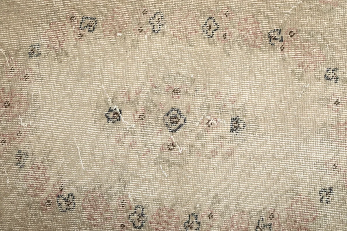 Close-up of the rug's central field, showing faded rose and charcoal motifs