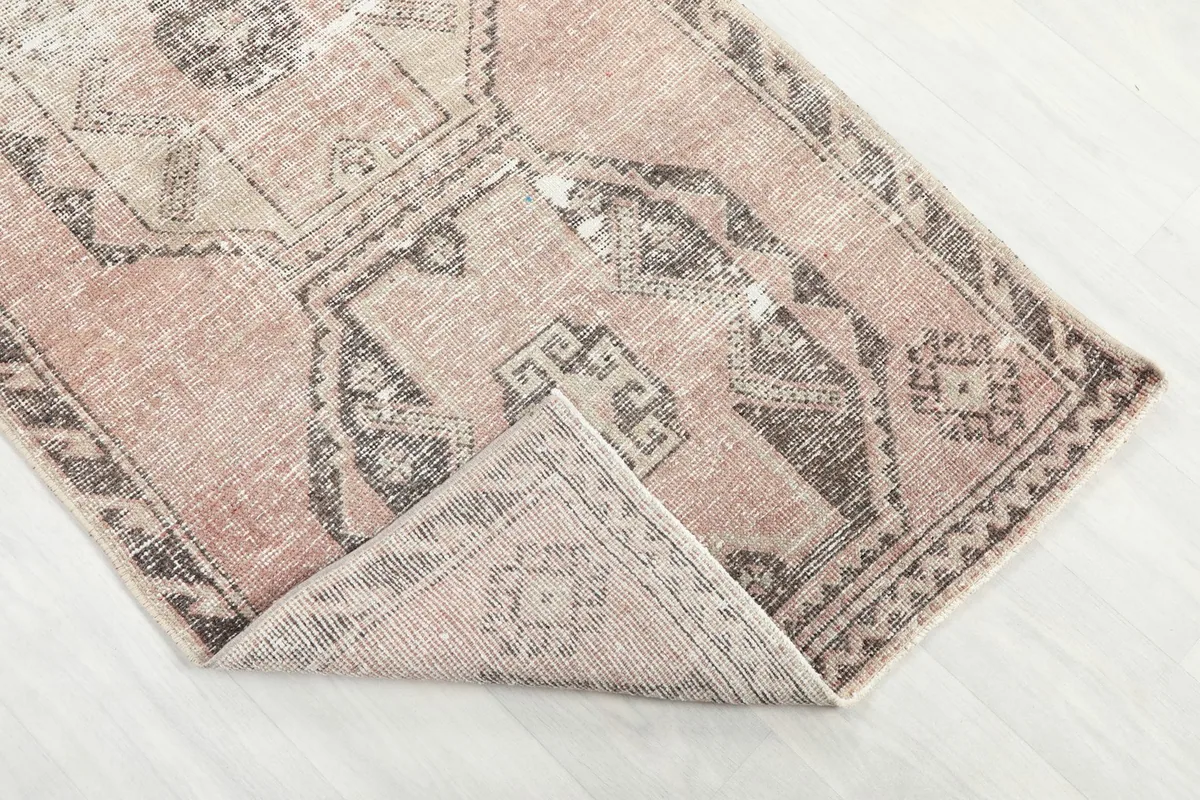 Corner of the runner rug folded back, showing the flexible hand-knotted construction and pile.
