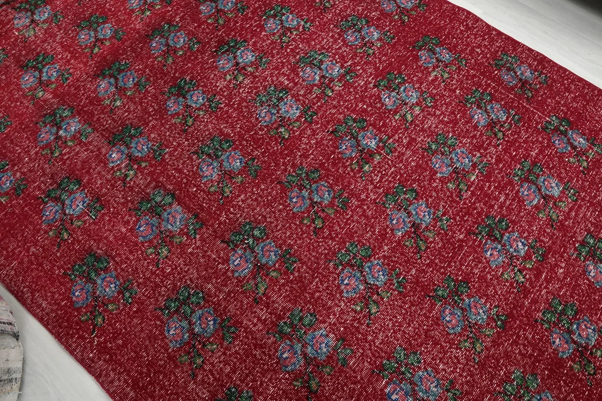 Diagonal view across the red floral rug, showcasing the repeating pattern and texture.