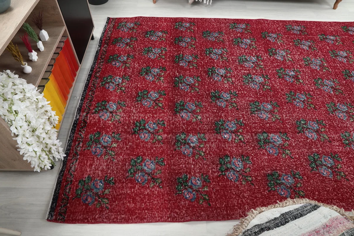 Another angle of the red floral rug in a room, capturing its placement and scale.