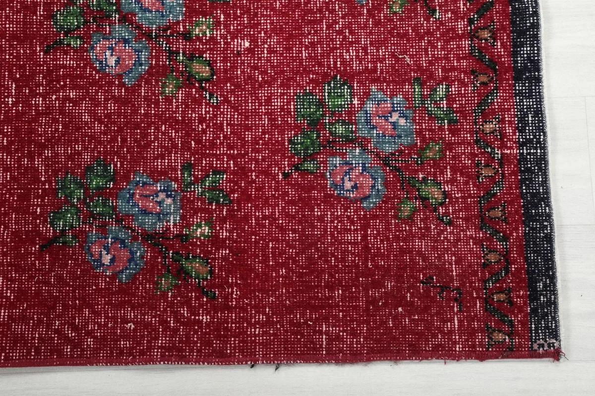 Close-up of the red field and a blue and pink floral motif with green leaves near the border.