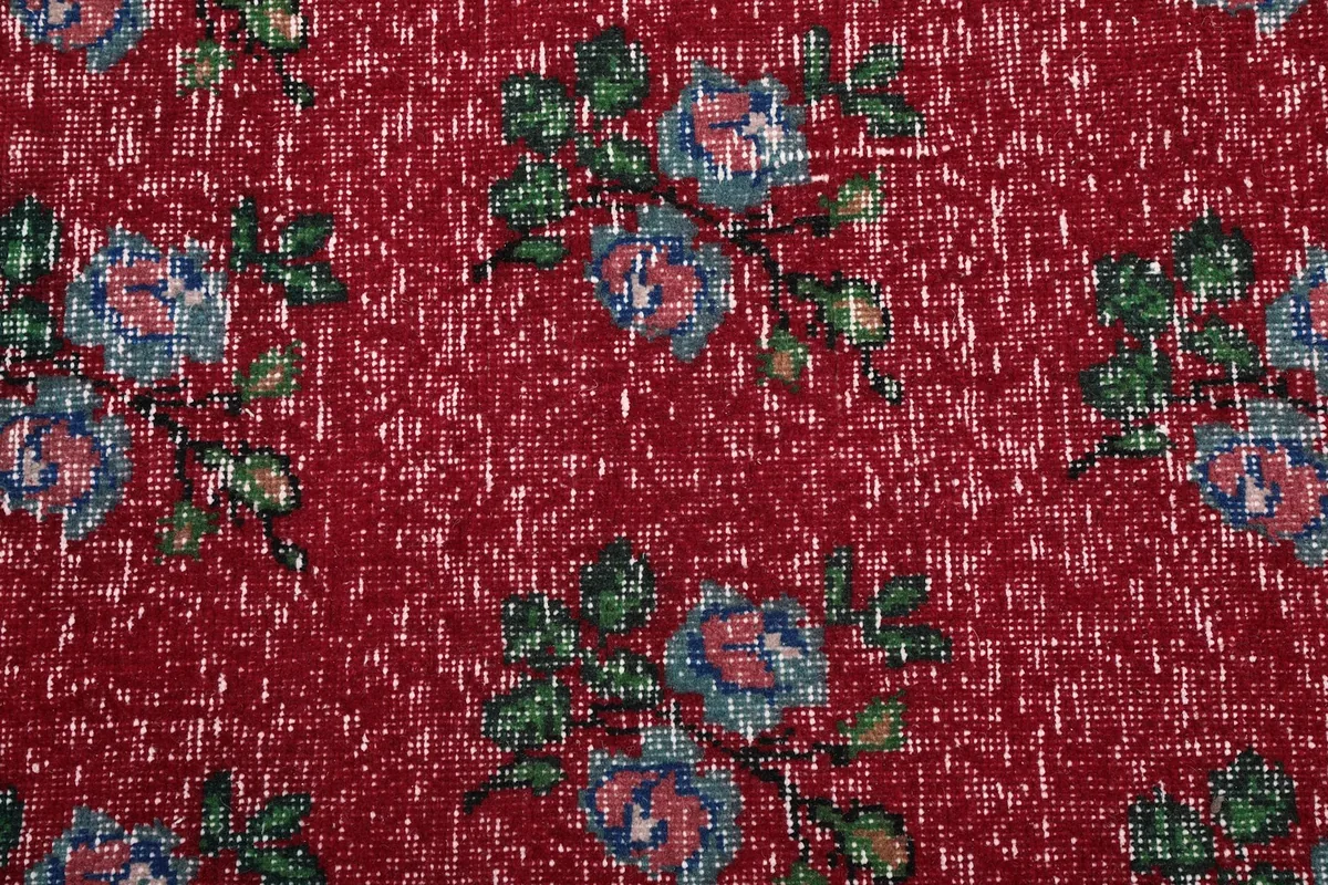 Detailed view of the hand-knotted wool pile and individual floral motifs in blue, pink, and green.
