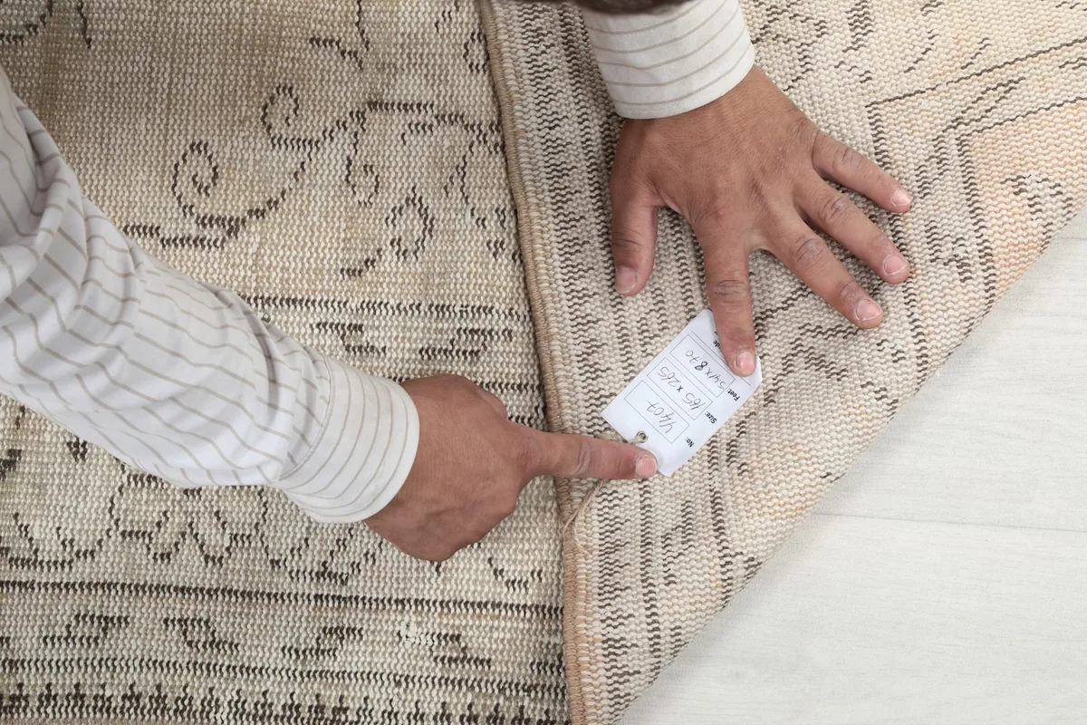 Hands pointing to the label on the back of the vintage Anatolian rug