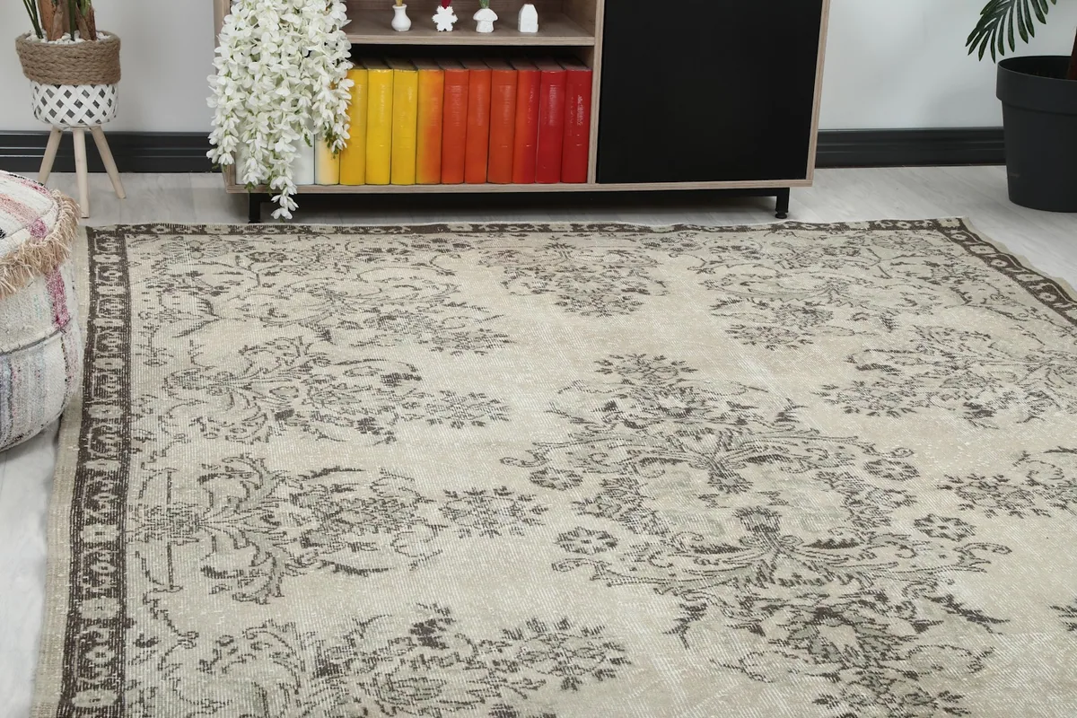 Close-up view of the rug's ivory field and faded gray floral motifs in a room