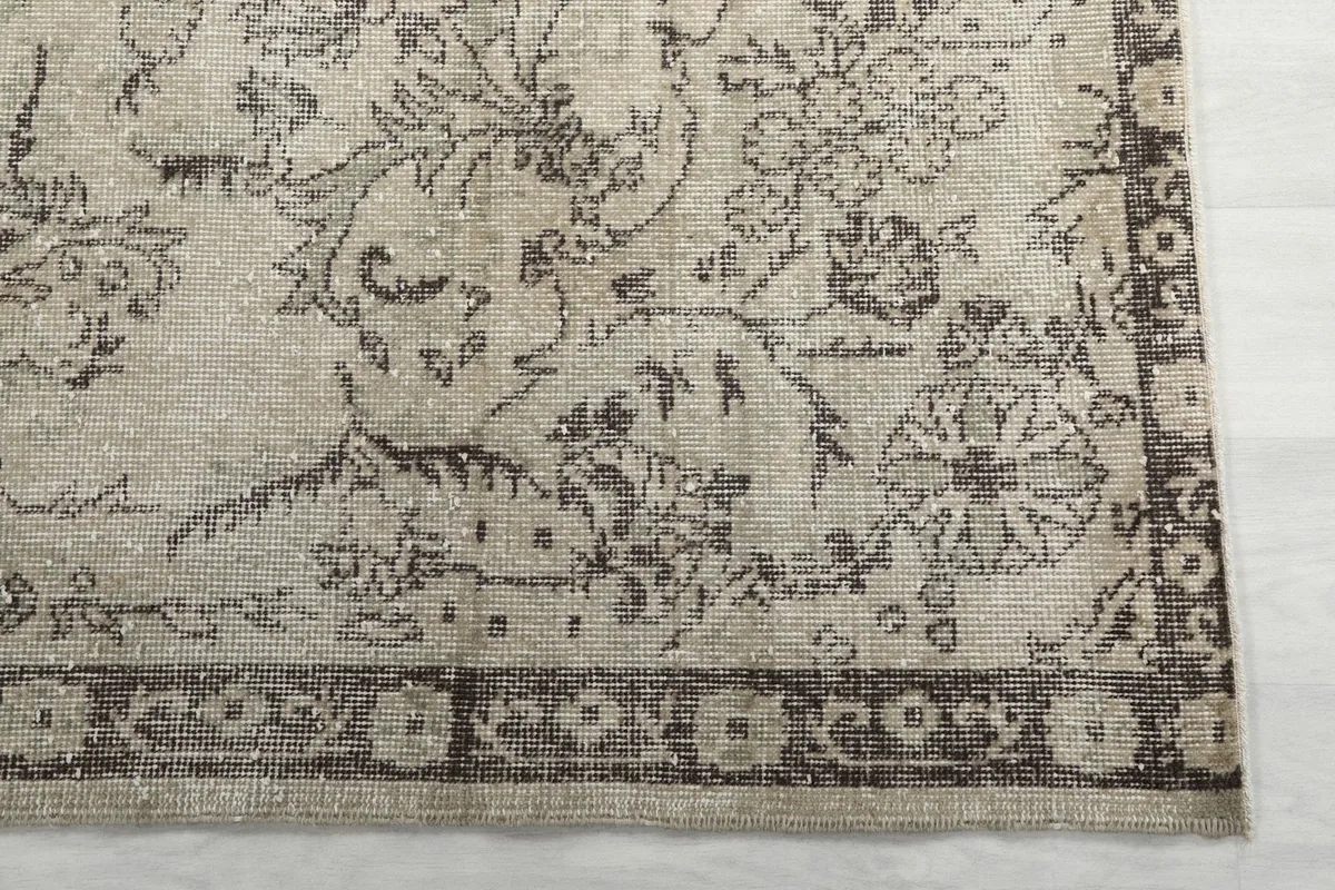 Detail of the rug's gray border pattern and corner, showing the distressed texture