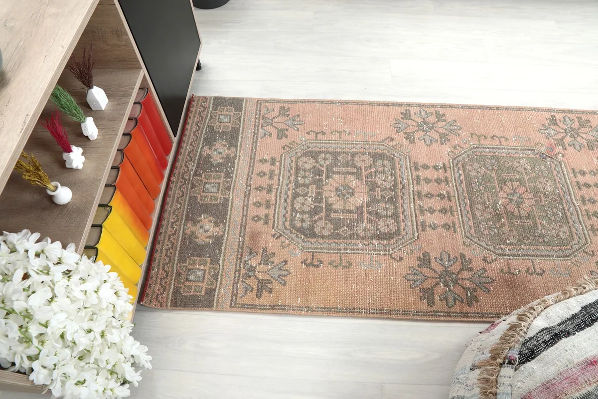 Angle view of the runner rug's pattern and colors in a room setting next to a shelf.