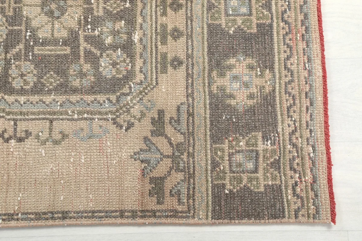 Detailed view of the rug's border and a geometric motif, highlighting color variations and texture.