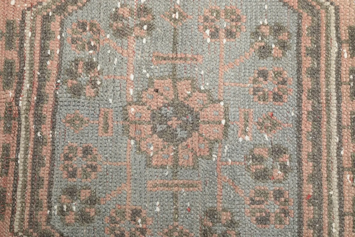 Macro detail of a central geometric medallion, showing the hand-knotted wool pile and faded colors.