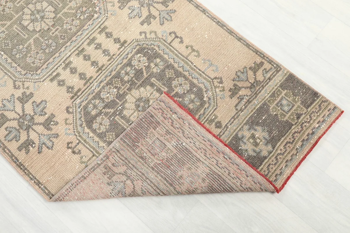 Corner of the rug folded to reveal the backside, showing the cotton foundation and knotting.