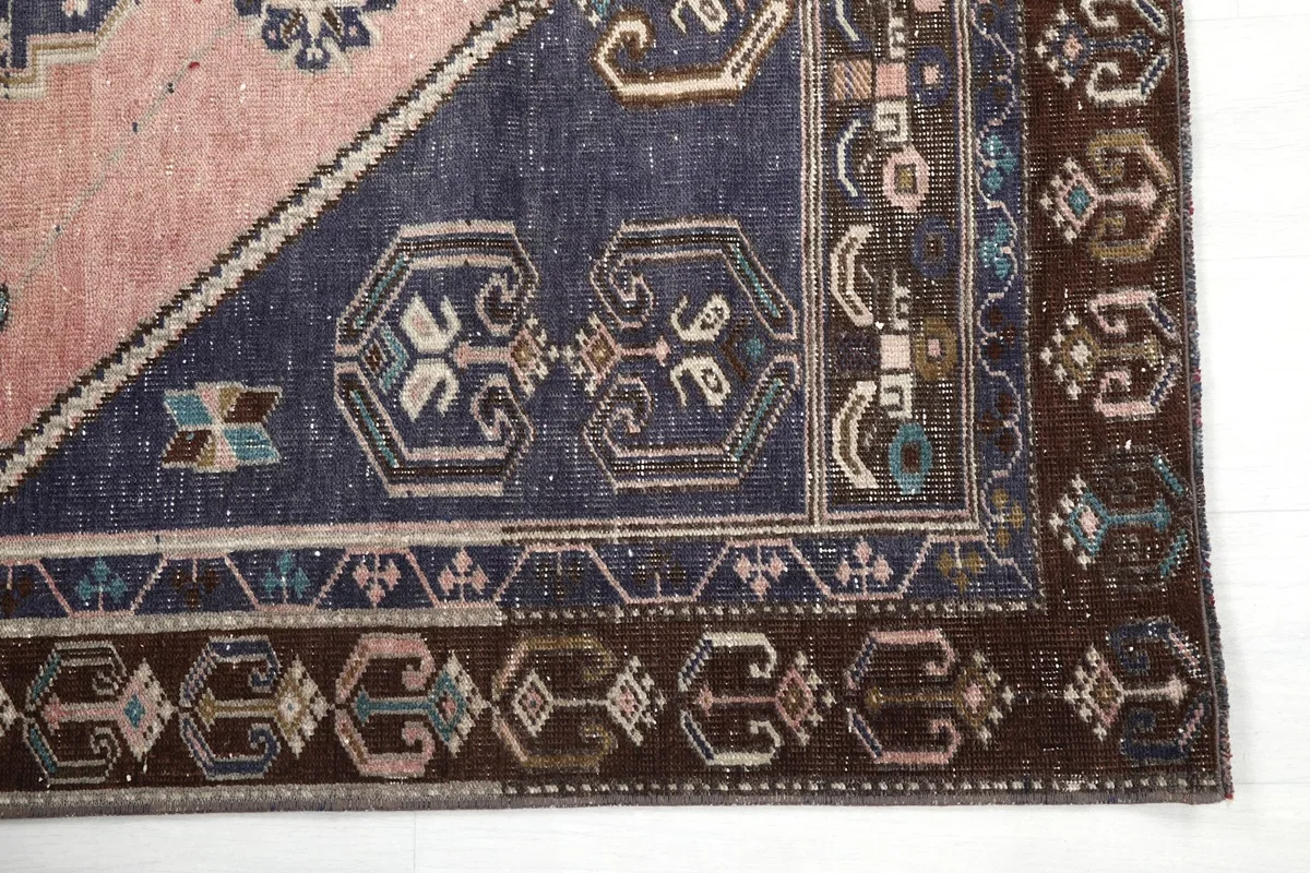Close-up of the rug's corner, showing navy and brown geometric patterns
