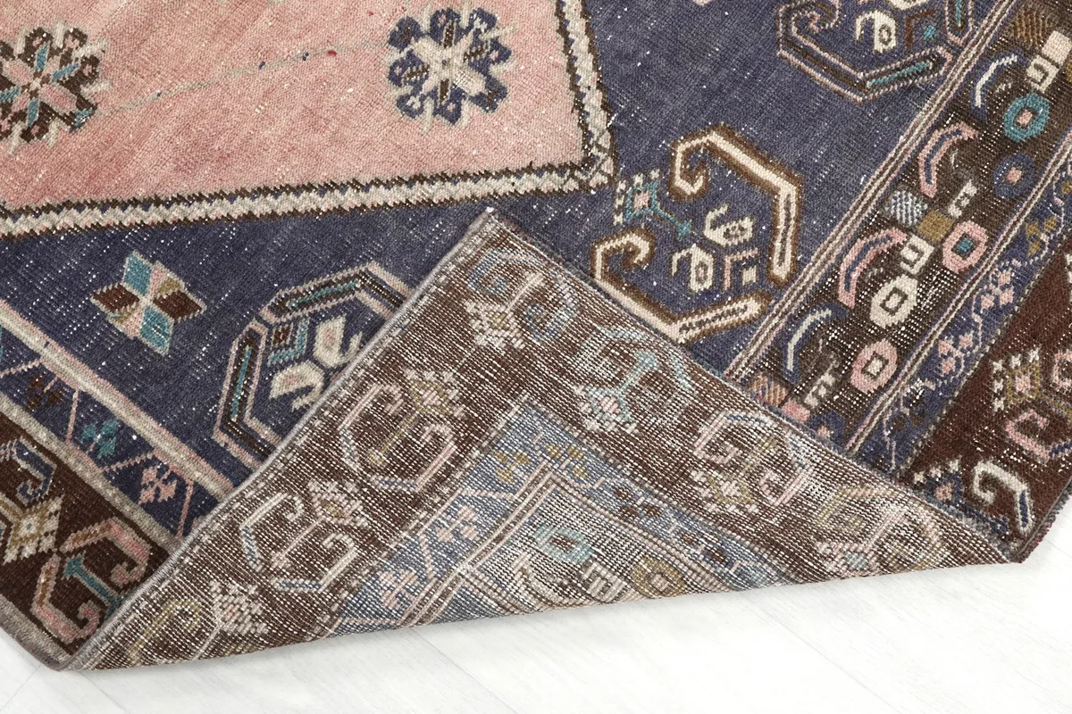 Corner of the rug folded back, revealing the hand-knotted cotton foundation