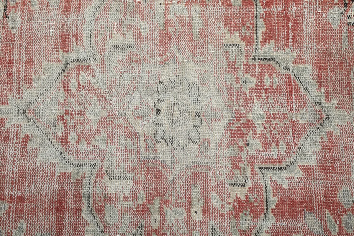 Close-up of a faded geometric motif within the rose field, highlighting wear.