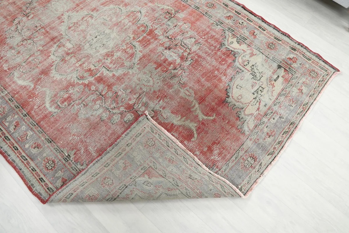 Corner of the rug folded back, revealing the reverse side of the hand-knotted cotton foundation.