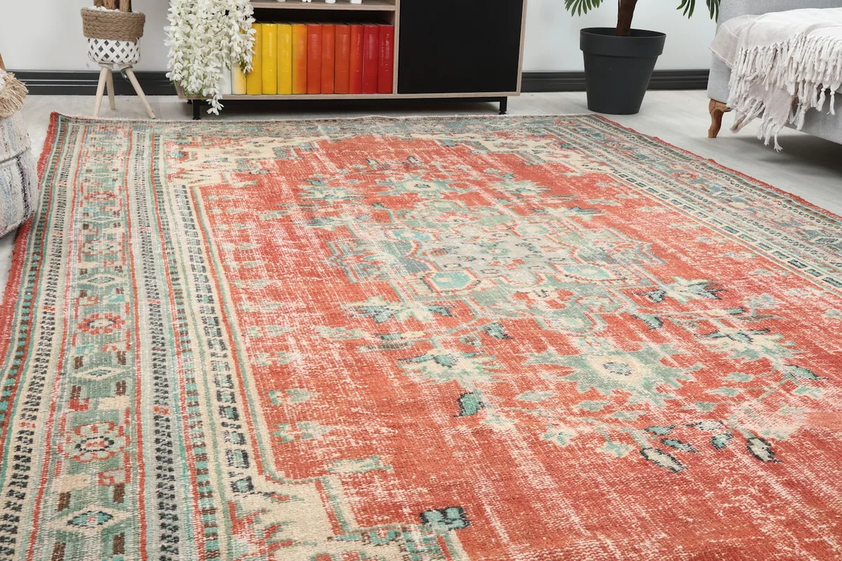 Close-up angle view of the rust rug's field and border patterns, showing texture and patina