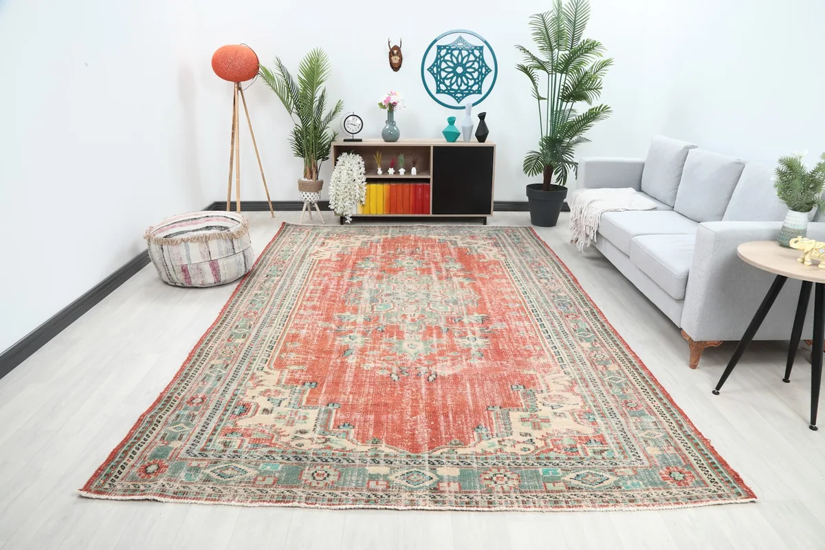Large rust area rug laid out in a modern living room setting with a sofa and plants